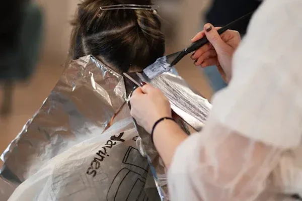 Hairdresser applying colour to a client's hair