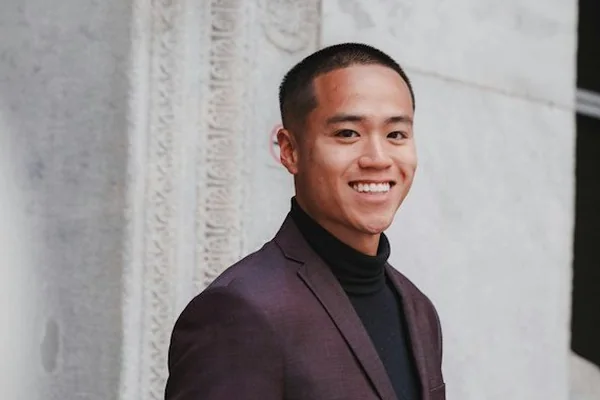 Smiling property agent in a dark suit outside a building