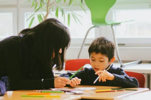Tutor and a young student working at a classroom table