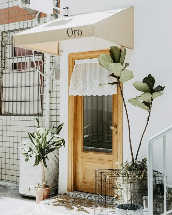 Front door of the studio under a cream awning with the Oro sign